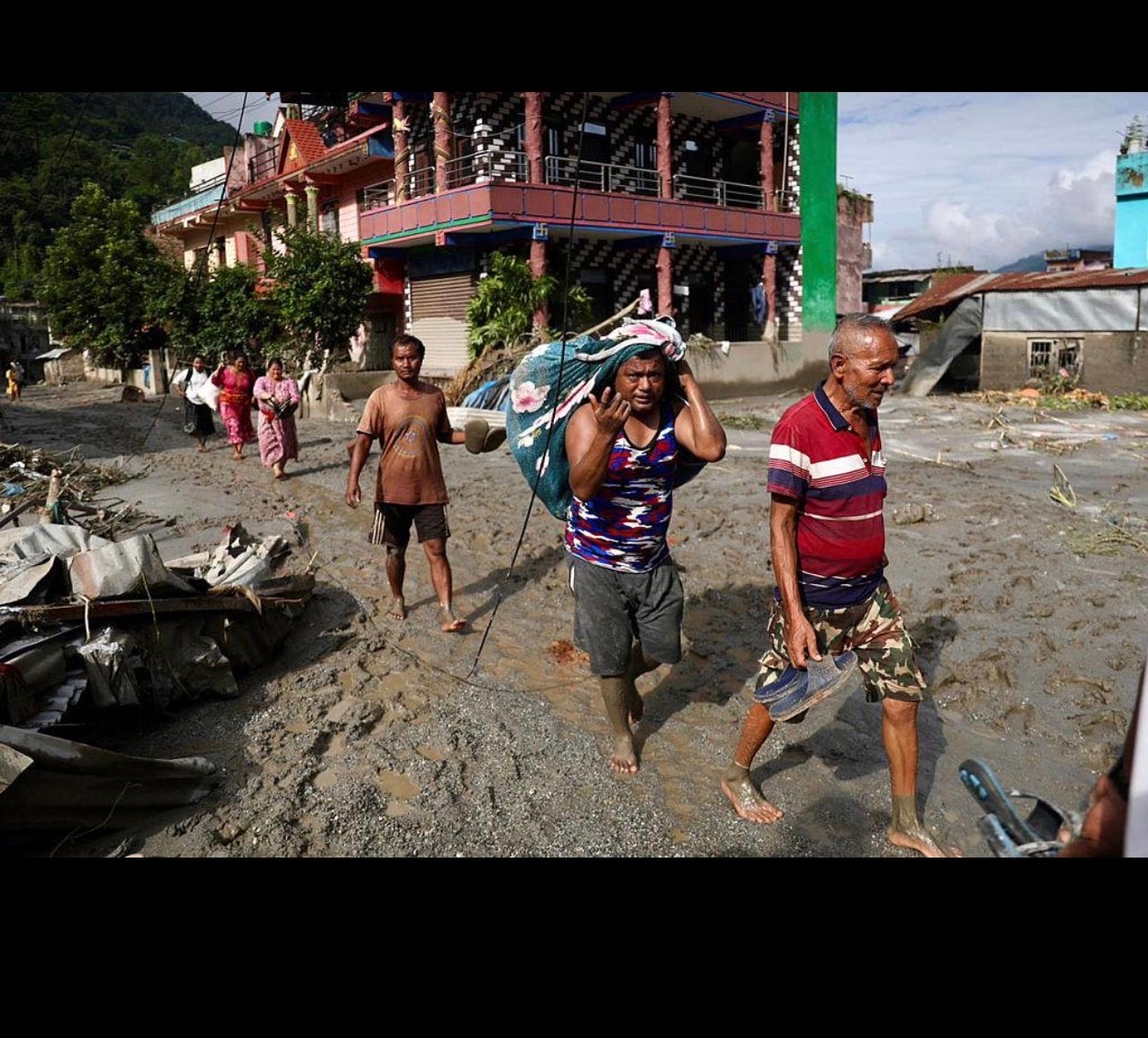 Survivors make their way through mud-covered streets in the aftermath of the flooding. (File photo)